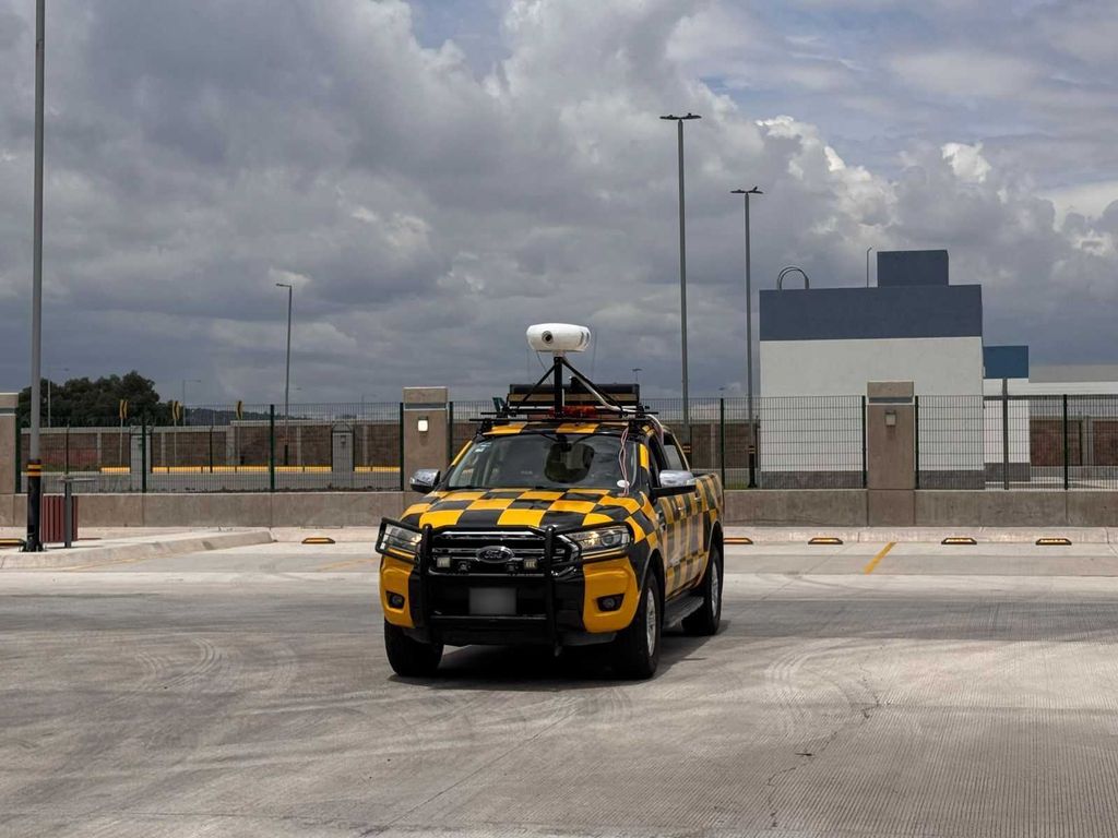An airport operations vehicle in high-visibility livery carrying an Oreyeon sensor unit on an apron.